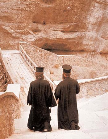 Due pope ritratti di spalle camminano verso un monastero, 1965 ca.